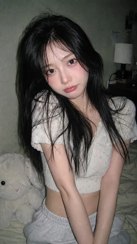 年轻黑发女性坐在床边，身穿露腰短针织衫与运动裤，在CCD直闪下注视镜头｜通用 / 未注明 生成