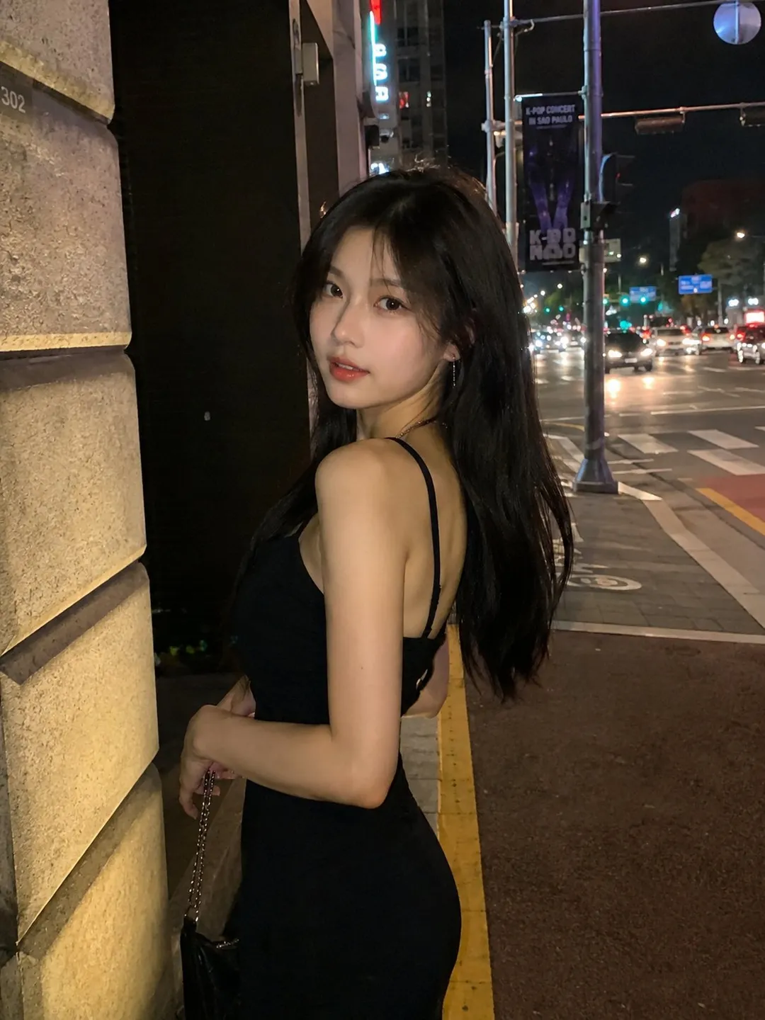 Young woman in a black slip dress turning towards camera on a Seoul night street, generated with GPT Image 2