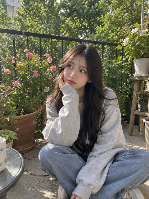 年轻女性穿着灰色卫衣坐在绿植环绕的阳台地面上托腮沉思｜GPT Image 2 生成