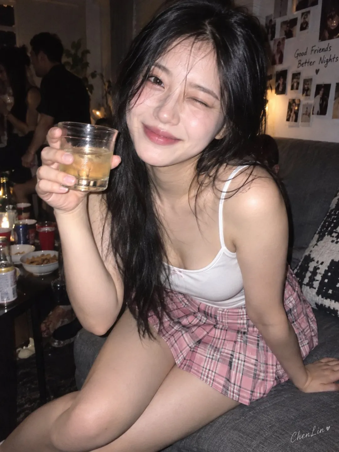 年轻女性身穿吊带背心坐在沙发上单眼眨眼举杯，直闪派对纪实摄影风格｜通用 / 未注明 生成