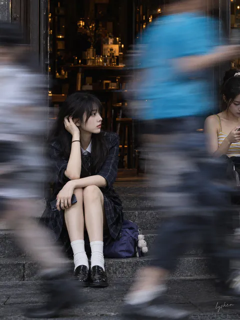 年轻女性坐在街边店铺台阶上，前方有行人走过的强烈运动模糊拖影, generado con 通用 / 未注明